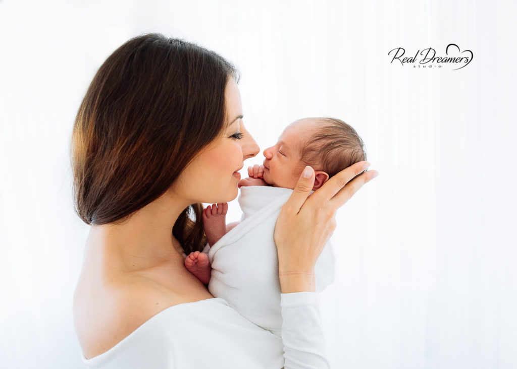 Cosa fare quando nasce un bambino: foto mamma con in braccio il suo neonato fasciato